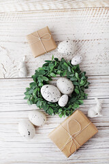 green wreath, eggs and bunny on white wooden background