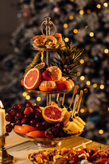 beautiful ripe tangerines lie in a plate on the table close-up with blurred background on the background of a Christmas tree decorated with garlands and Christmas toys, Christmas mood.
