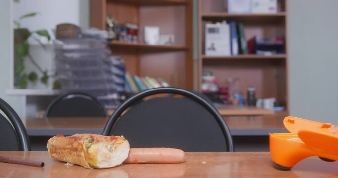 Impudent dachshund puppy put its paws on table and wanted to eat ingredients for the hot dog, which human left unattended, but owner caught pet and drove it away. 