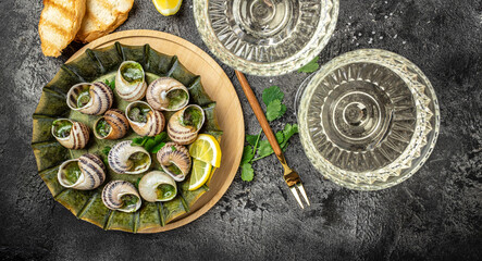 Fototapeta na wymiar Fried snails Escargots de Bourgogne with herbs, butter, garlic on metal plate with forks, wine glass. gourmet food. Restaurant menu, dieting, cookbook recipe