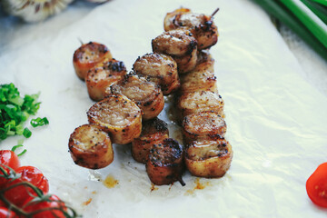 Shashlik or shish kebab prepared on barbecue grill over hot charcoal with grilled vegetables. Grilled pieces of pork meat on metal skewers.