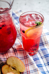 Fototapeta na wymiar Fresh berry and fruits lemonade in a jug and glass on the napkin