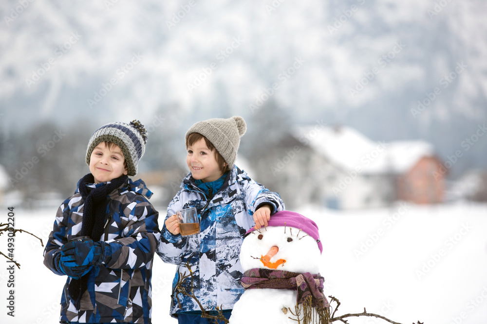 Canvas Prints Family with children, building snowman in the park in little village in Austria