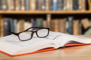 Old books, reading glasses on the wooden desk