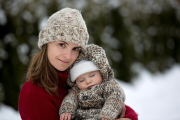 Beautiful mother and cute baby boy in knitted onesie, having taken their beautiful winter outdoor portrait