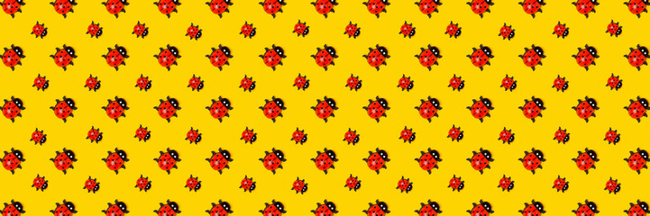 Banner made with pattern of ladybugs on yellow background, as backdrop or texture. Bright summer wallpaper. Top view Flat lay.