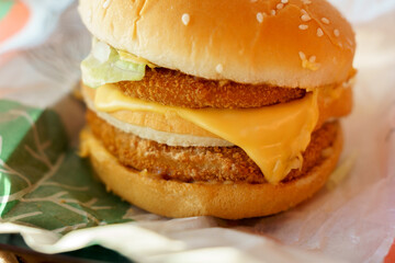 Big grilled chicken burger with double cutler and cheese, close-up. Selective focus