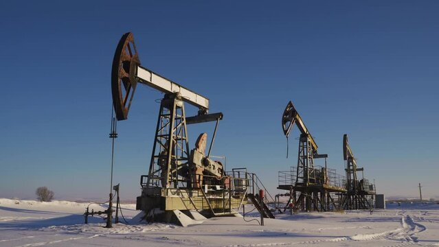 Oil pumps on a winter sunny and frosty day. Oil production in a snowy winter