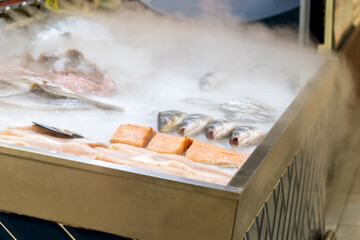 Fresh fish on the shelves of the hypermarket, cooled by cold steam. Selective focus