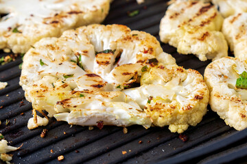 Cooking cauliflower steak with herbs and spices. Healthy vegetarian snack, close-up.