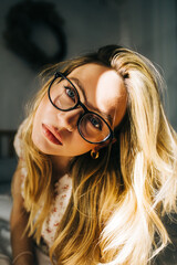 Portrait of attractive caucasian woman with blonde hair in eyeglasses, sunset light.