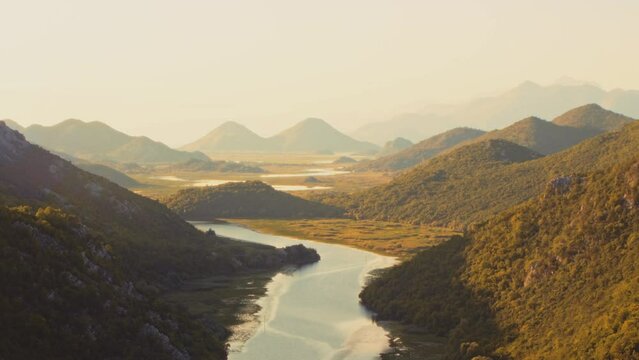 Mediterranean river valley with mountain peaks on the horizon at dawn. Crnojevica River Canyon sunrise. Timelapse. Warm colors.