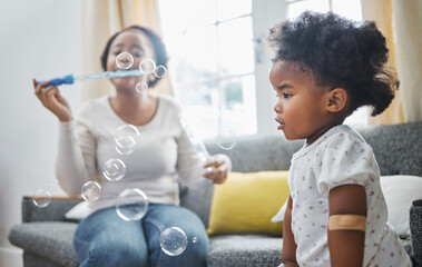 I can pop them one by one. Shot of a young mother and daughter having fun with bubbles at home.