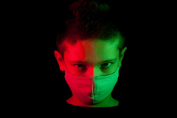 A portrait of the boy wearing in a mask with red and green light making a 3D effect on the dark background