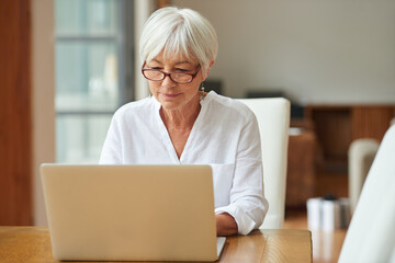 Connected to information from the comfort of home. Shot of a senior woman using a laptop.