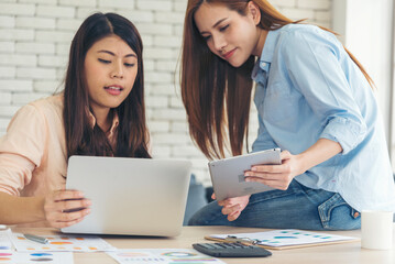 Asian colleague friendship at work with smiling face. Happiness two women colleague working together team meeting in office desk. Team business partners working with computer laptop startup company