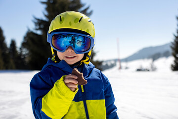 Cute toddler child in colorful ski wear, skiing in Italy on a sunny day, kids and adults skiing...