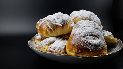 delicious sweet pies are sprinkled with powdered sugar on a black background. delicious