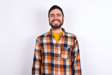 Obraz premium young caucasian man wearing plaid shirt over white background with nice beaming smile pleased expression. Positive emotions concept