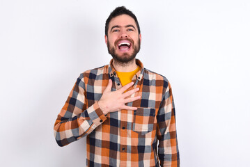 Fototapeta premium young caucasian man wearing plaid shirt over white background smiles toothily cannot believe eyes expresses good emotions and surprisement