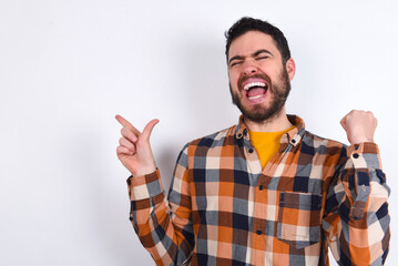 Fototapeta premium Cheerful young caucasian man wearing plaid shirt over white background showing copy space ad celebrating luck