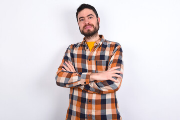 Fototapeta premium Confident young caucasian man wearing plaid shirt over white background with arms crossed looking to the camera