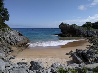 Fototapeta na wymiar Small golden sandy beach between rocks on the Atlantic coast. Horizontal view. 