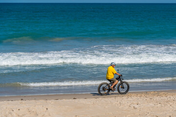 Fototapeta na wymiar A Man Riding Bike on Beach