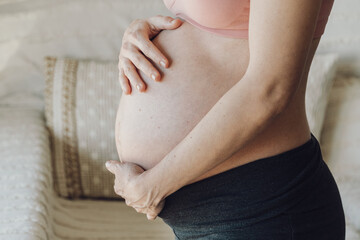 Silhouette of young woman holding her hands on pregnant belly.