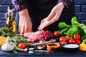 chef is sprinkling salt on strip loin steaks