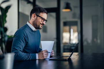 Man getting ready for an online meeting, holding papers, looking