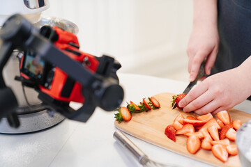camera takes a video for a cooks or pastry chef in kitchen. cutting strawberries