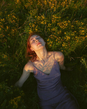 Redhead woman laying in grass outdoor with sunlight