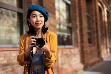 Fototapeta na wymiar Beautiful Chinese woman with camera. Happy smiling woman taking photos of beautiful location..