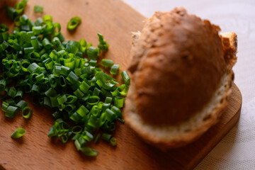 chopped green onions on a wooden board and bread