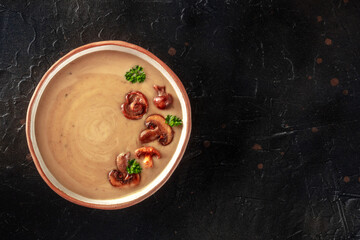 Mushroom soup, garnished with parsley, shot from the top on a black slate background with a place for text