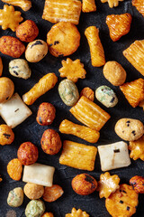 Japanese rice crackers assortment on a black slate background, top shot