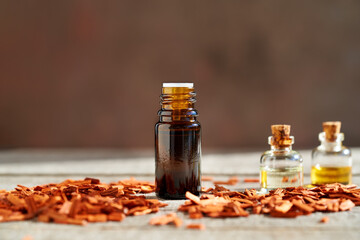 A bottle of sandalwood essential oil with red sandalwood chips on a table