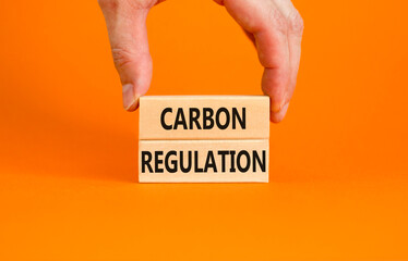 Carbon regulation symbol. Concept words Carbon regulation on wooden blocks on a beautiful orange table orange background. Businessman hand. Business and carbon regulation concept, copy space.