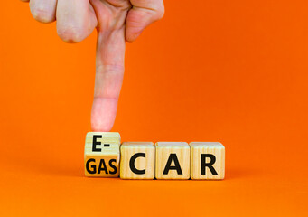 Gas car or e-car symbol. Businessman turns a wooden cube and changes words Gas car to E-car. Beautiful orange table orange background, copy space. Business and gas or electric car E-car concept.