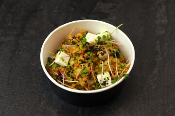 Healthy vegetarian bowl with red lentil, feta cheese and greens isolated on dark background. Food delivery service and daily ration concept.