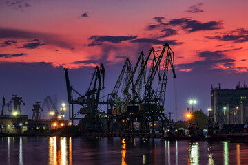 the silhouette of port cranes, at stunning twilight .