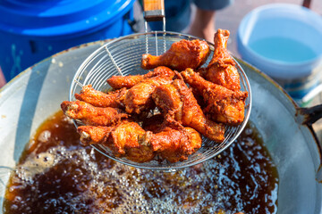 Chef cooking crispy fried chicken in oil hot pan on street food market in Thailand.