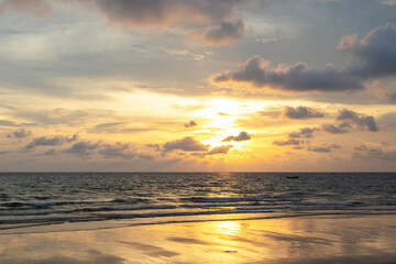 Yellow sunset at the beach.There were dark clouds like it was going to rain background. Waves, sky and yellow sun. Amazing sea waves hitting the coast background. The sun resort vacation evening. 