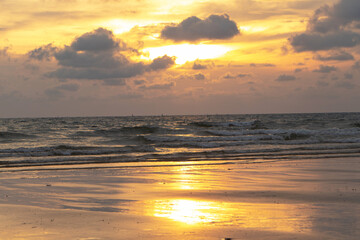 Yellow sunset at the beach.There were dark clouds like it was going to rain background. The sun resort vacation evening.  Waves, sky and yellow sun. Amazing sea waves hitting the coast background.  © Thepporn