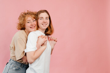 Expression of love of lesbian couple. Two young girls hugging and enjoying each other on pink background. Cute couple celebration of Valentines Day. Romantic gesture concept