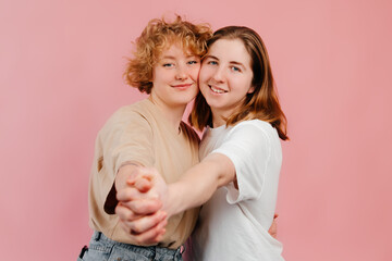 Happy lesbian couple dancing tango, stretching their arms to the camera, looking at the camera and smiling. Valentines day celebration concept