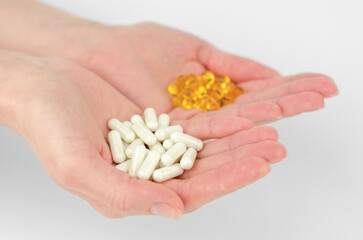White capsule pills in female hands, selective focus