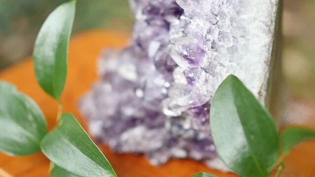 Close up view of amazing flashing amethyst cluster on a table on a table during beautiful rare sparkling mineral stone. Shiny Purple rough Amethyst quartz crystal.