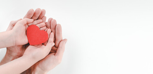 Hands of father and son holding red heart on white background, heart health insurance, family day, world heart day